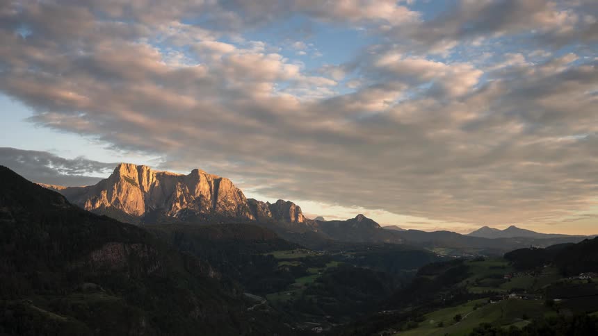 A landscape of a mountain range with the sky full of clouds passing quickly