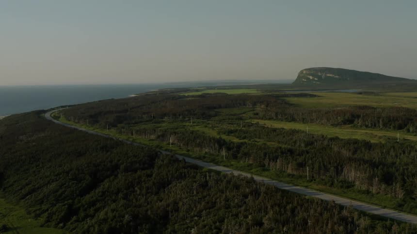 Road winds along the top of a forested mountain overlooking a foggy landscape