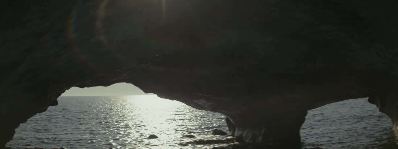 View of the sea through a large opening in a rock formation