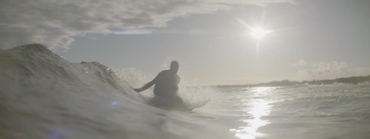 A surfer stands and rides a small wave