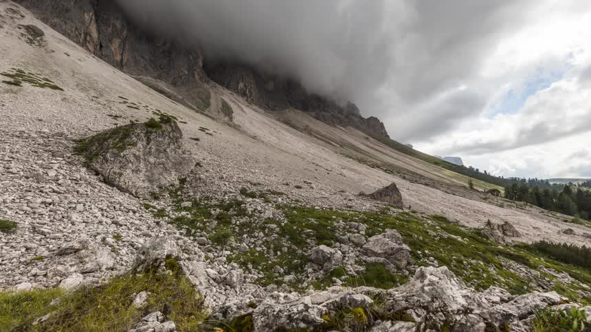 A mountain with its peak covered in a dense cloud passing quickly