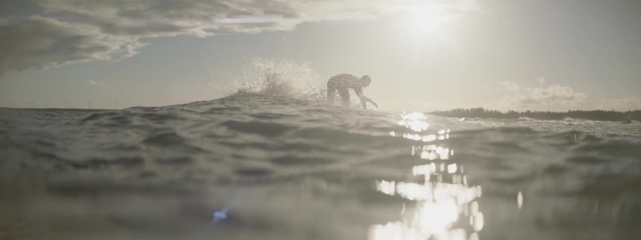 Surfer riding a small wave as seen from a water level camera