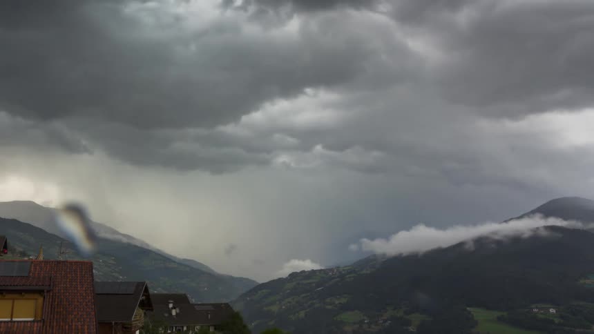Landscape under a stormy sky with thunder with dark clouds foreshadowing a storm over mountains and houses