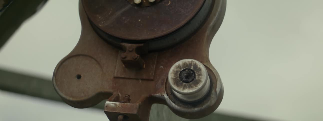 A rusty pulley hanging from an outdoor structure