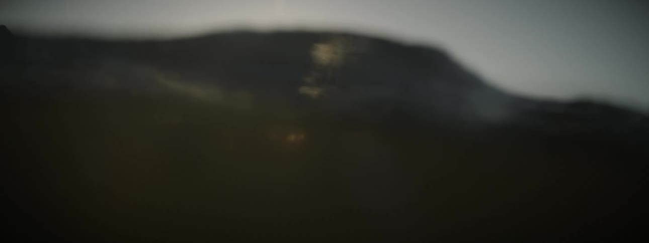 A surfer is paddling his surfboard in late afternoon
