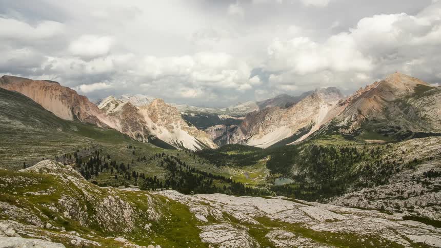 Clouds pass over a mountain lined valley in this time lapse