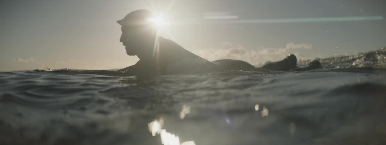 A man paddles while floating on his surfboard