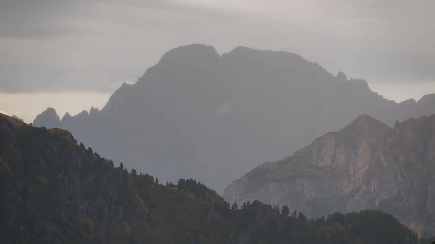 Dense fog partially obscures mountain range under an overcast sky