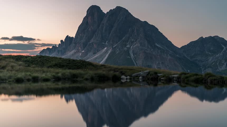 Time lapse of sunrise over a mountain range next to a tranquil lake