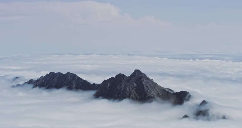 Thick clouds obscure everything except the top part of a mountain range