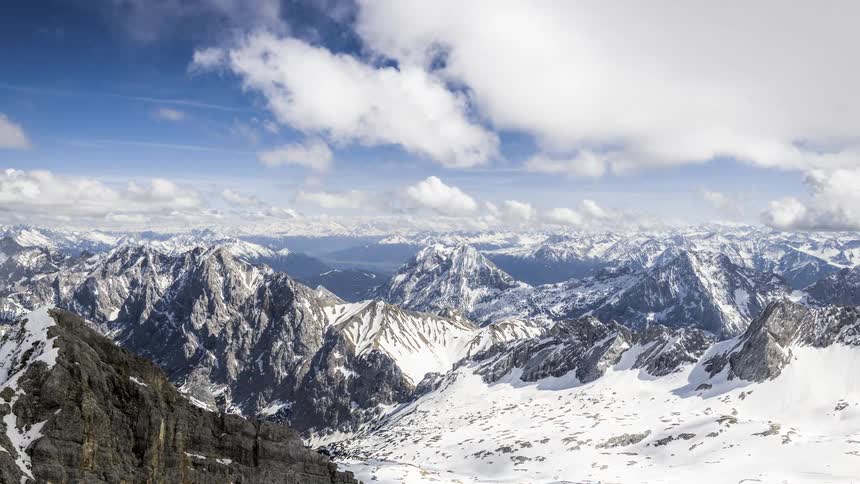 Vast snowcapped mountain range under a partly cloudy sky
