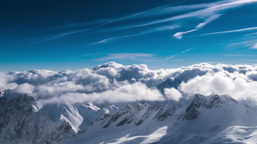 Cumulus clouds move over a snowcovered mountain range