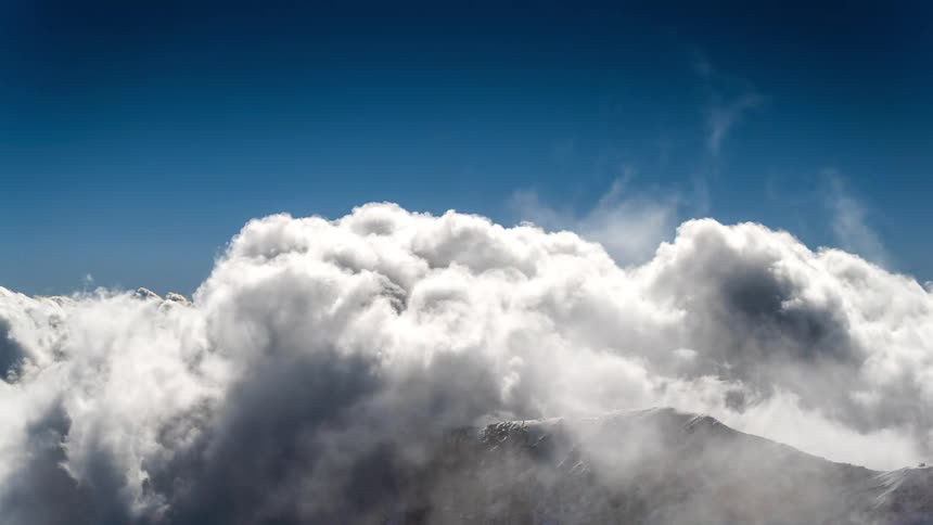 Mountain peak covered by clouds passing by in time lapse