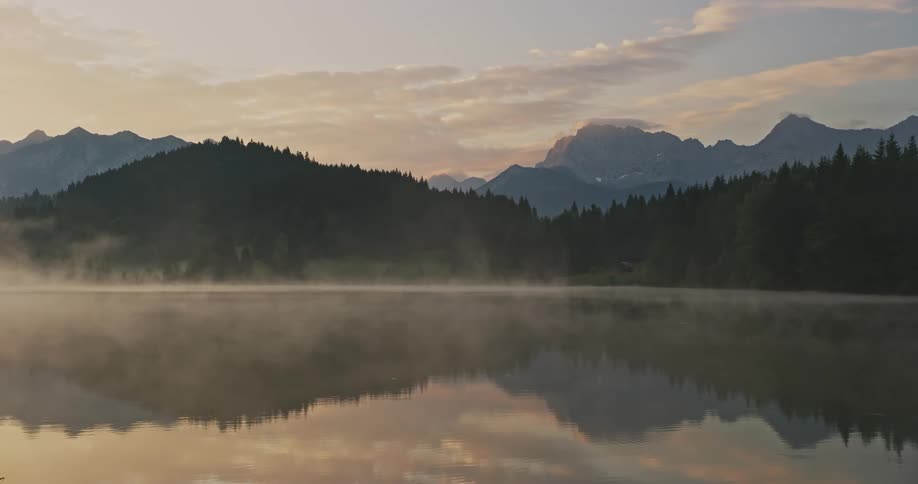 Natural scenery of a lake in a morning that reflects trees and mountains around