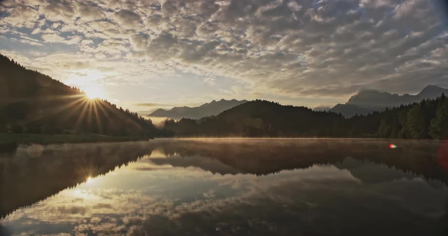 Sunrise landscape over a lake with mountains and trees around