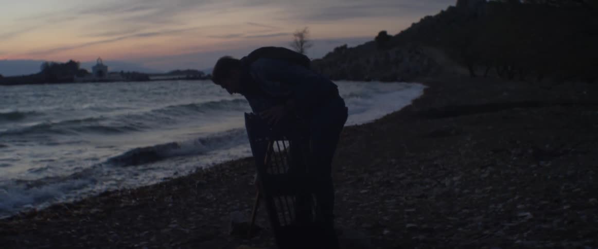 A man building something on the beach at dusk