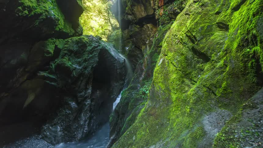 The waterfall pours into the stream
