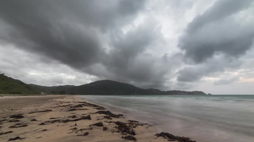 Clouds pass over beach as waves flow onto the sand