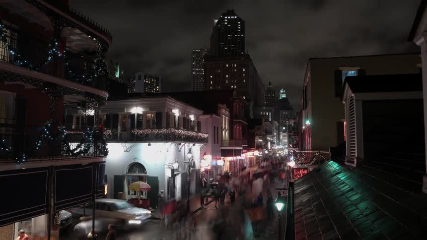 Pedestrians and traffic move through a city street at night