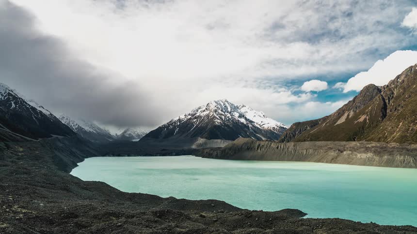 Clouds move over a river flowing between mountain ranges