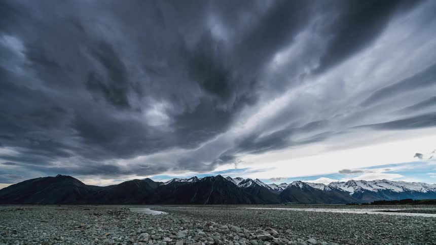 Dramatic landscape with a dark cloudy sky over snowy mountains