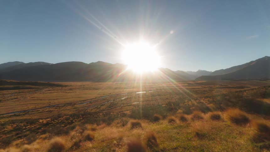 The bright sun sets behind the mountains