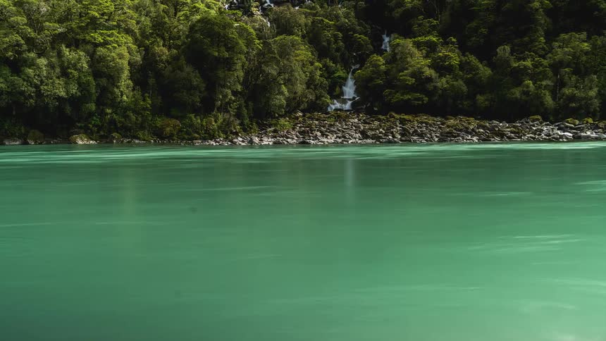 Greenish flowing lake surrounded by forested mountains
