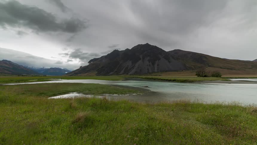 Dark clouds move over a mountain near a river
