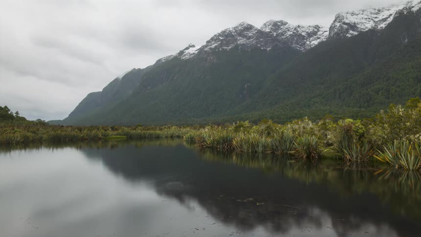 A lake reflecting an environment with a snowcapped mountain