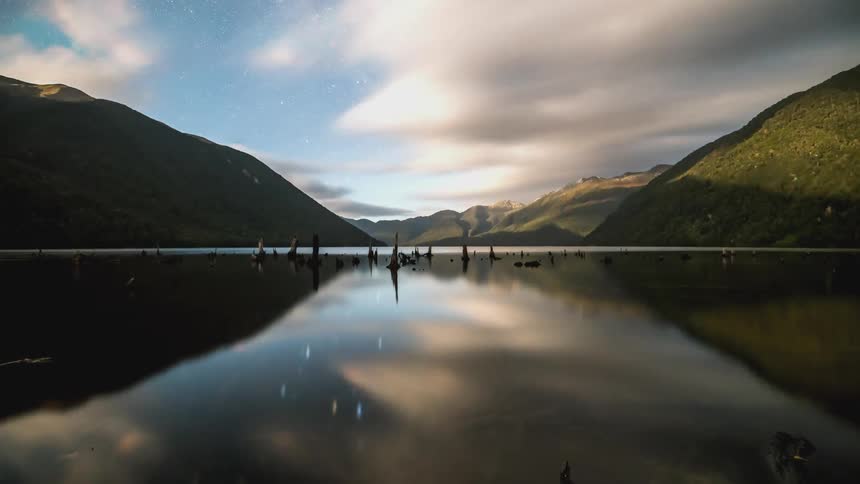 Time lapse of a starry night turning to dawn over a lake in the mountains