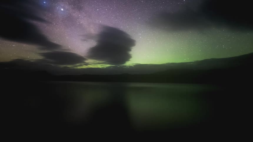 Time lapse of a colorful aurora over a lake on a starry night