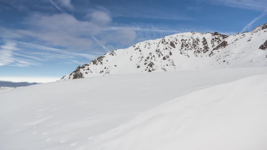 Snowy mountains against the blue sky with clouds