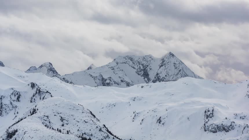Misty clouds passing above snowy mountains