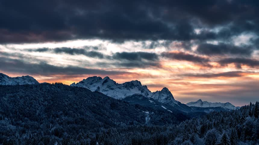 Time lapse of rolling clouds on a dramatic sunset over the snowcovered mountains