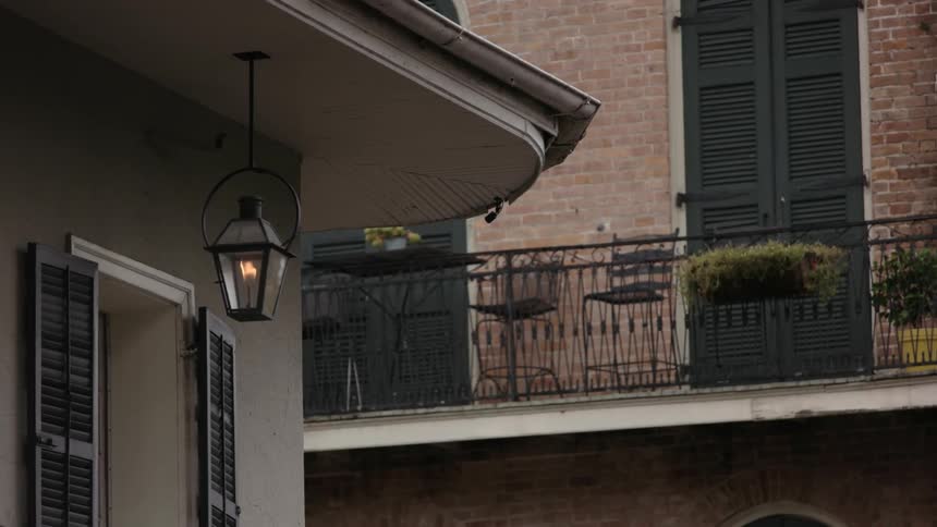 A flame is burning in a gas lamp hanging from a building during the day