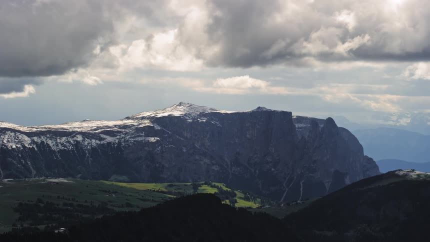 Landscape of greenish and snowy mountains with clouds passing by