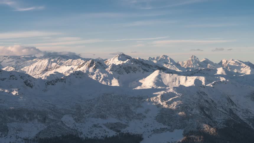 Snowy peaks and mountains against a blue sky with clouds