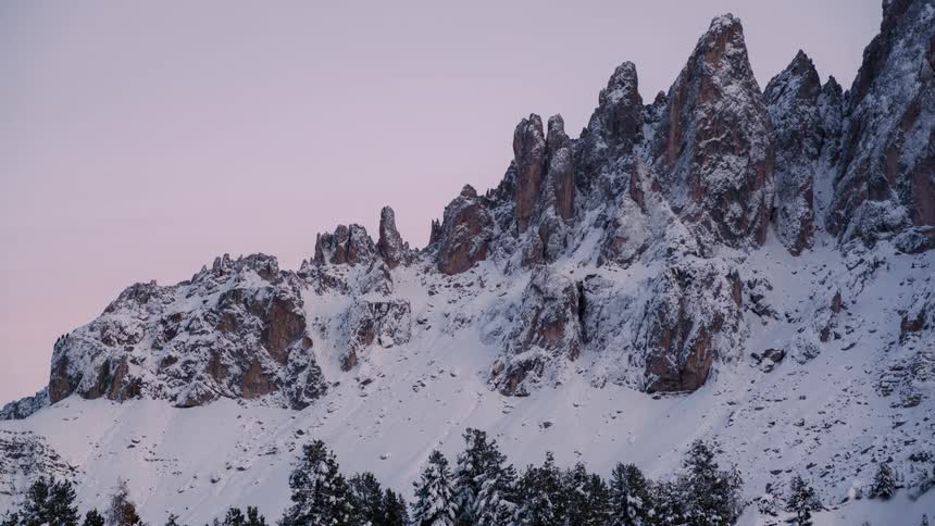 Snowcapped mountain peaks under a soft pink sky