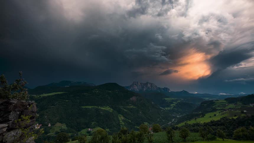 A giant storm creates a rainbow over a mountain range