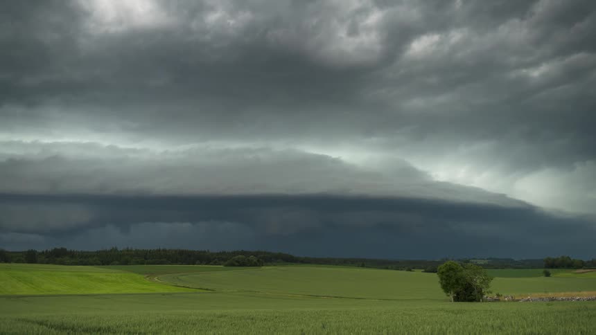 Time lapse of storm clouds rolling over a rural landscape next to the mountains