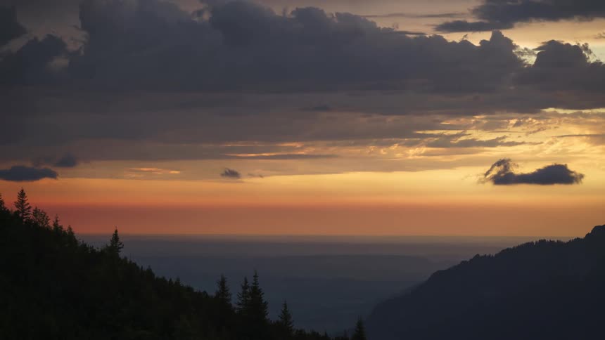 Mountain range with trees against a reddish seal and with clouds