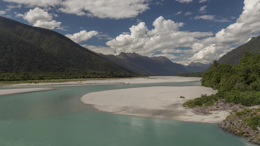 Water flows past beaches in a mountain valley