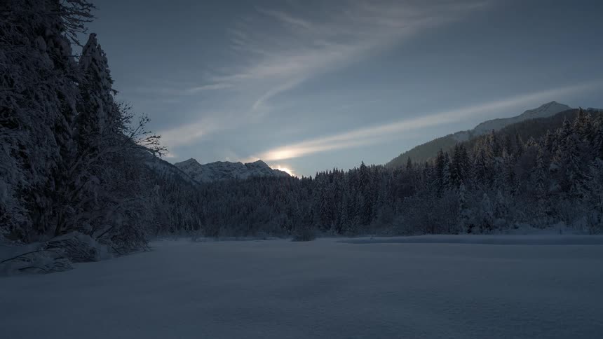 Time lapse of the sun setting over the mountains at winter