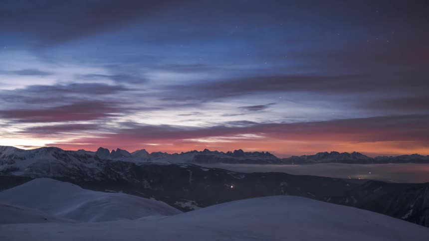 Clouds pass over snowy mountains as night turns to day