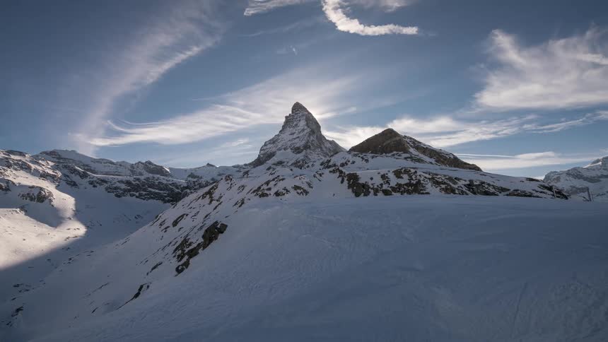 Mountain range with snowcapped peaks and clouds passing by