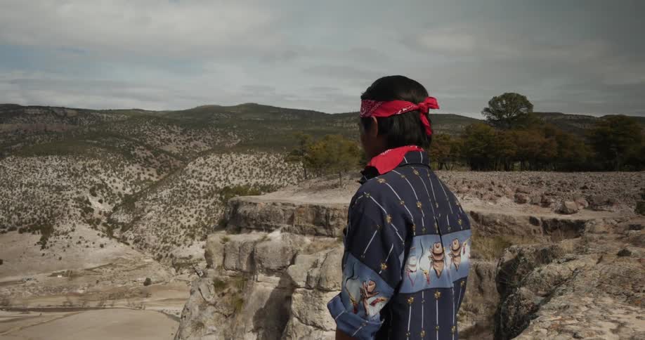 A man stands on a mountain looking over the valley below
