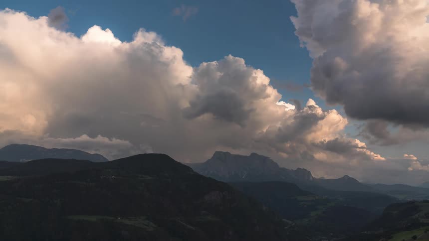 White clouds turn to storm clouds over a large mountain range