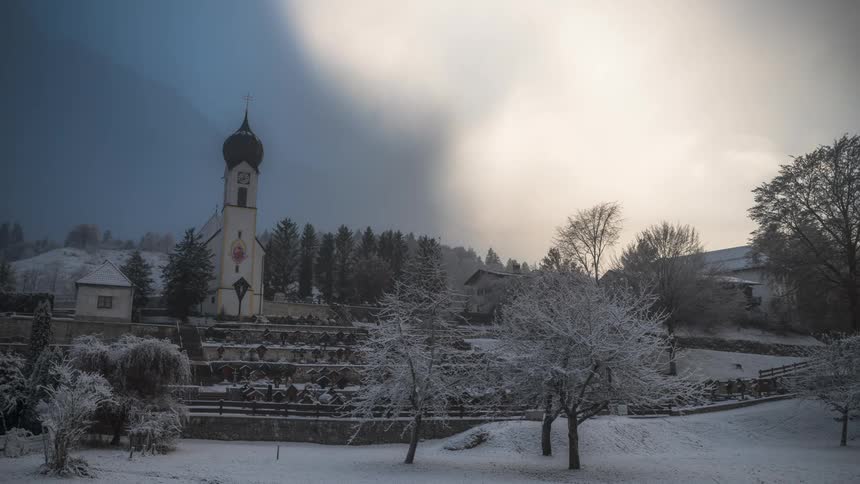Church surrounded by trees and covered by snow on a cloudy day