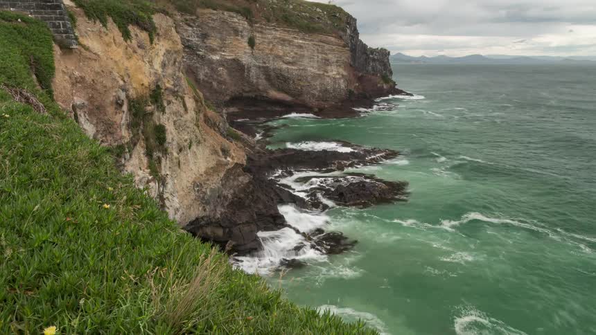 A lighthouse is by the cliff on the shore