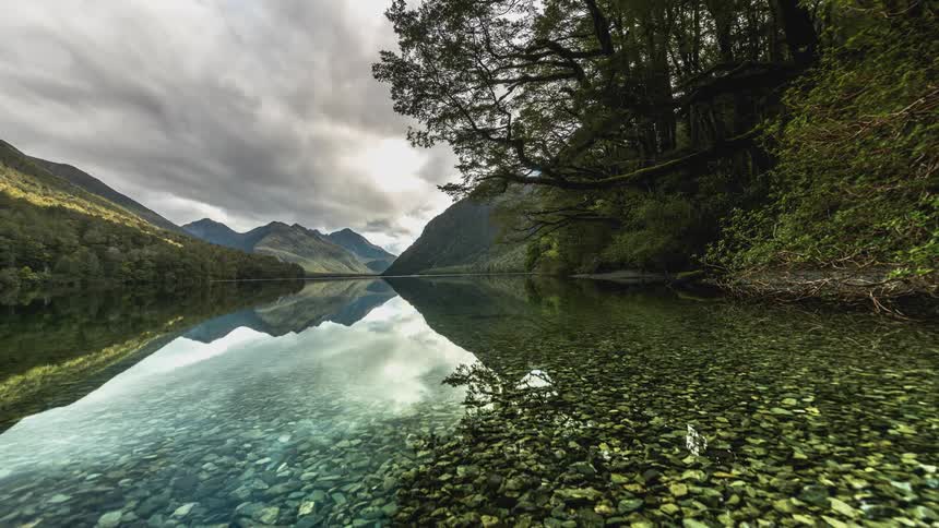 Water reflects the mountains as clouds flow overhead